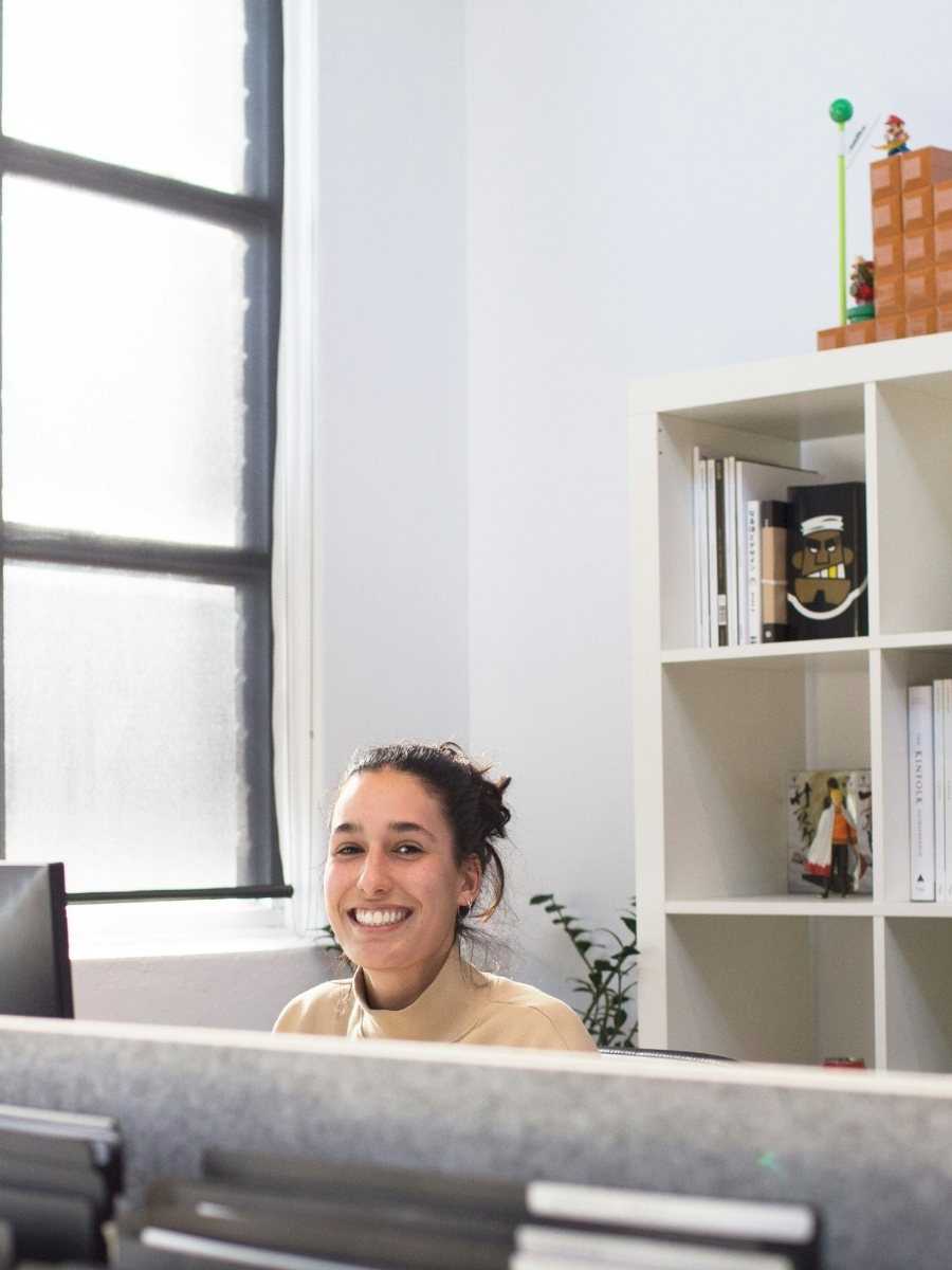 Collaboratrice souriante à son bureau dans un espace lumineux