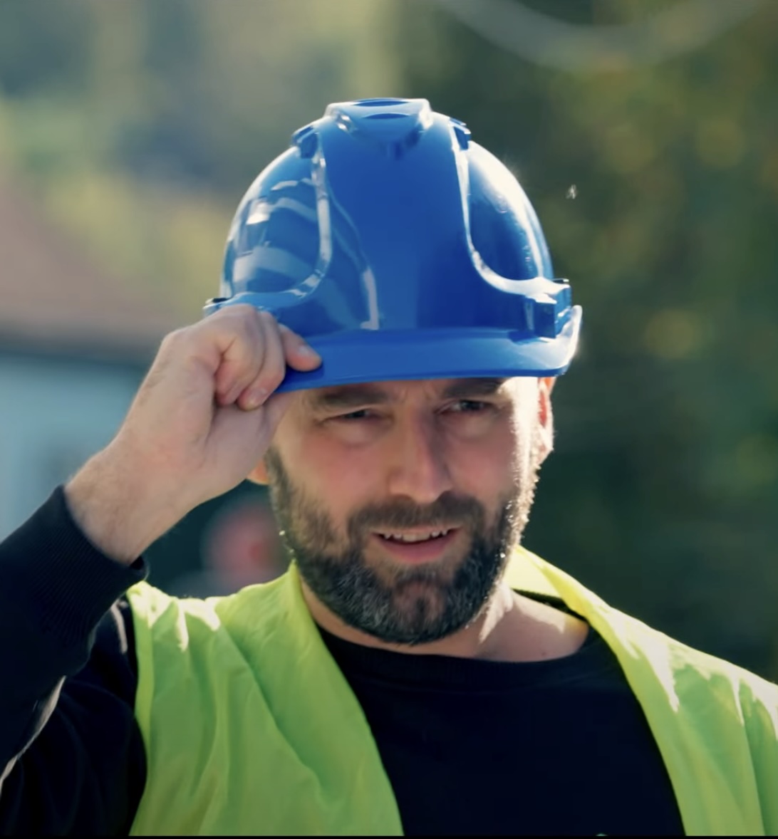 Travailleur souriant avec casque bleu et gilet jaune